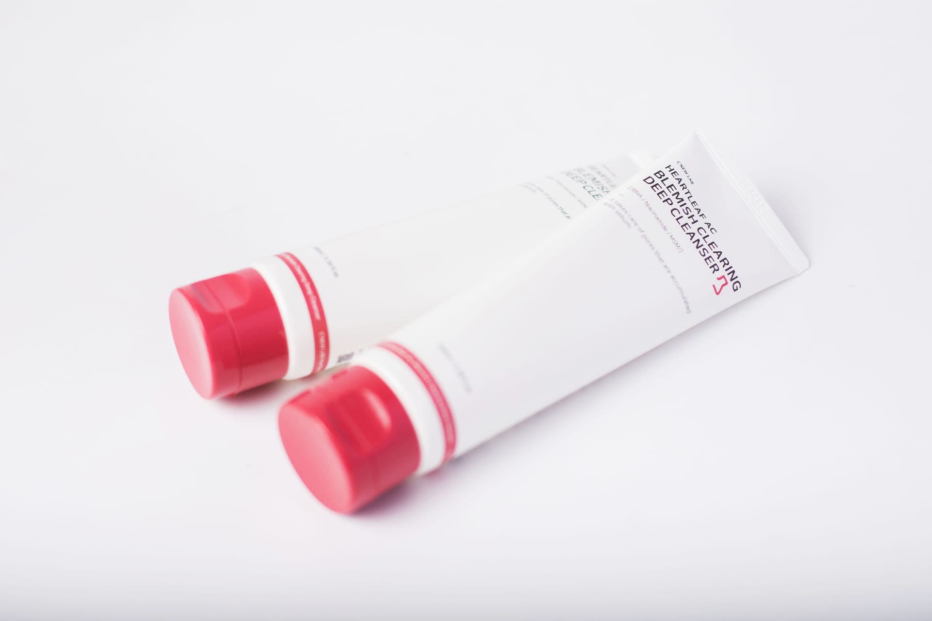 Two skincare tubes side by side on a pale surface
