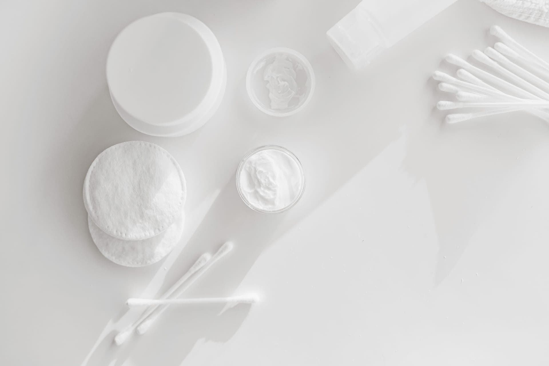 A cotton pad and an open jar of cleansing balm
