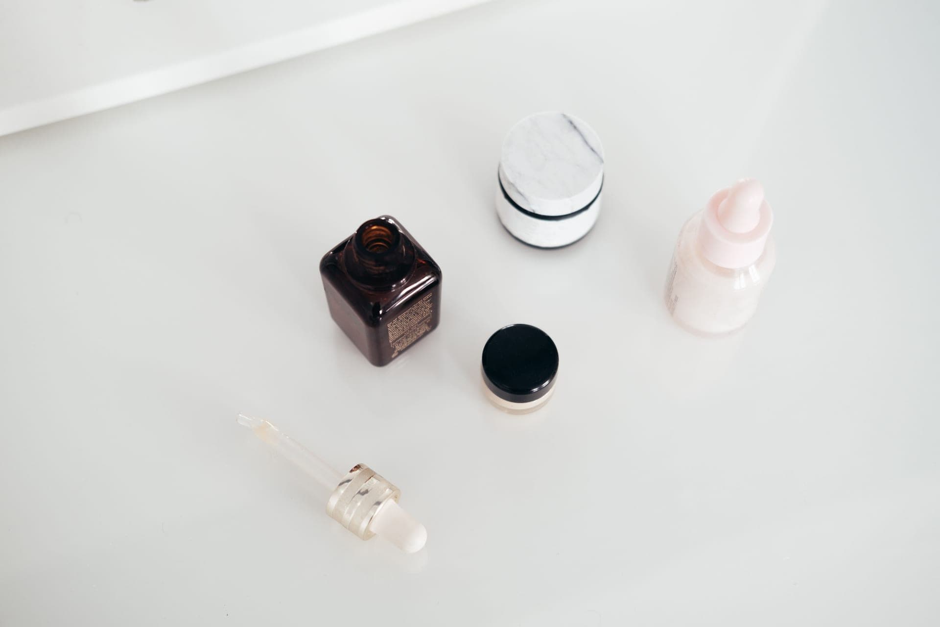 A glass dropper bottle beside an open cream jar