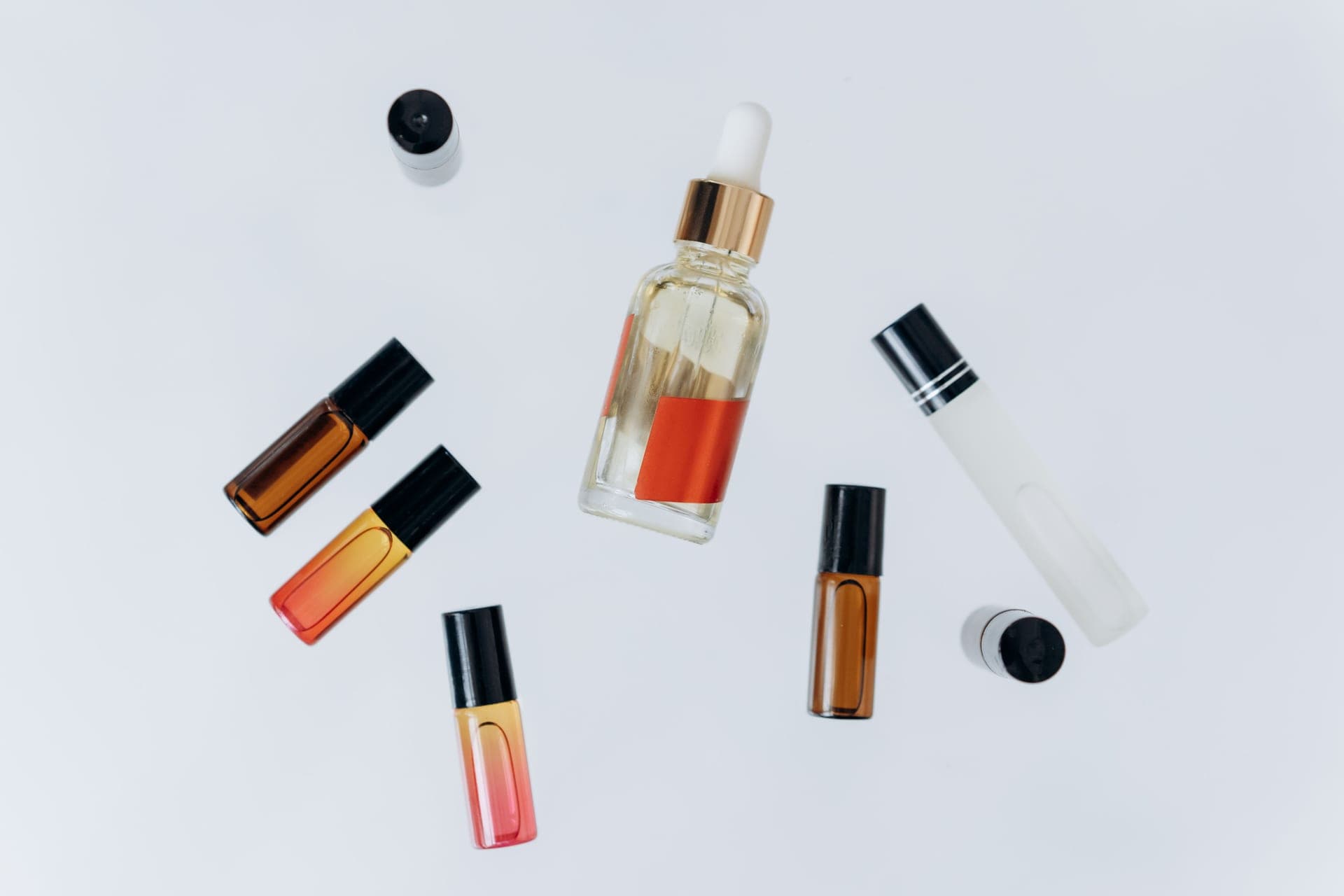 A roll-on oil bottle beside a glass perfume flacon