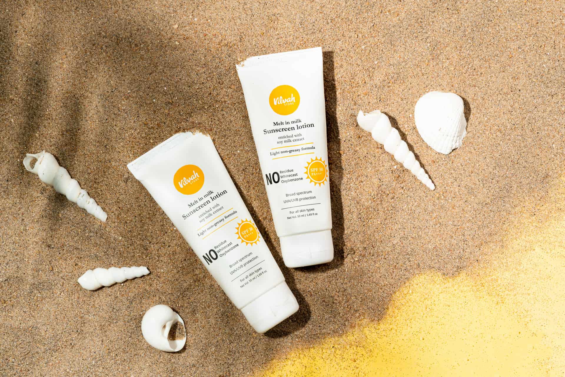 A sunscreen stick and a bottle of sunscreen lotion on sand