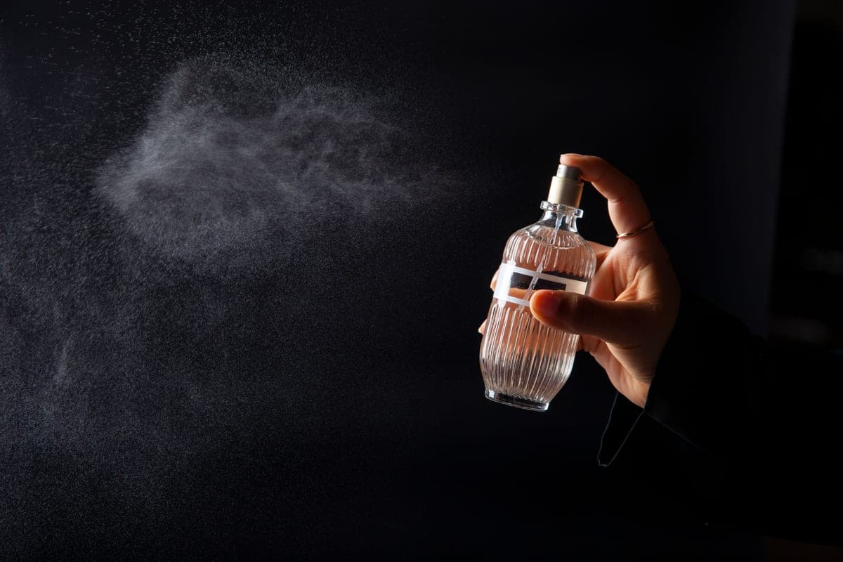 Fragrance mist caught mid-air against a dark background