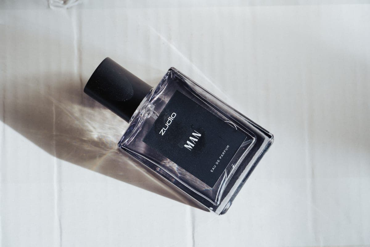 A dark cologne bottle photographed in low, warm light
