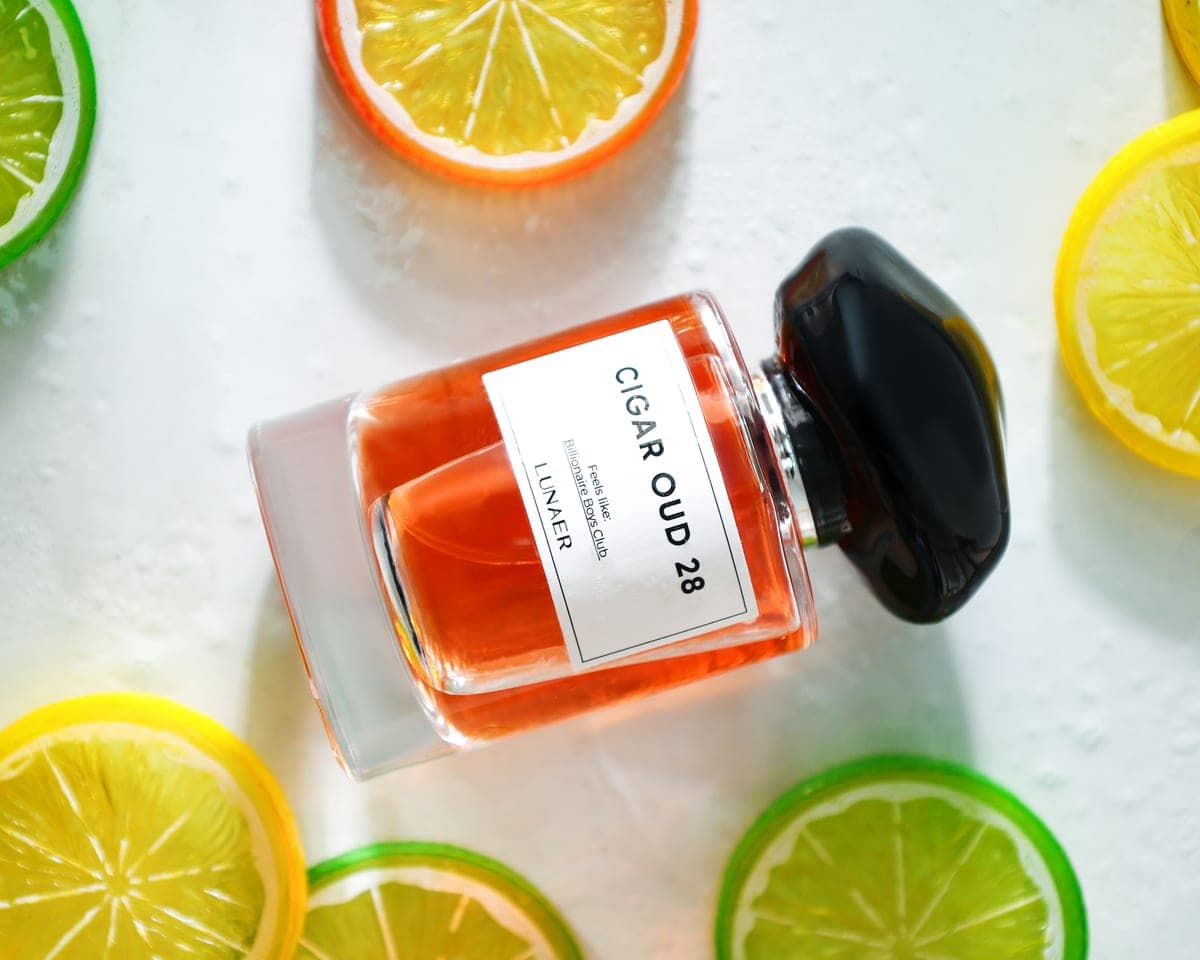 A citrus-toned fragrance bottle catching bright light against a dark background
