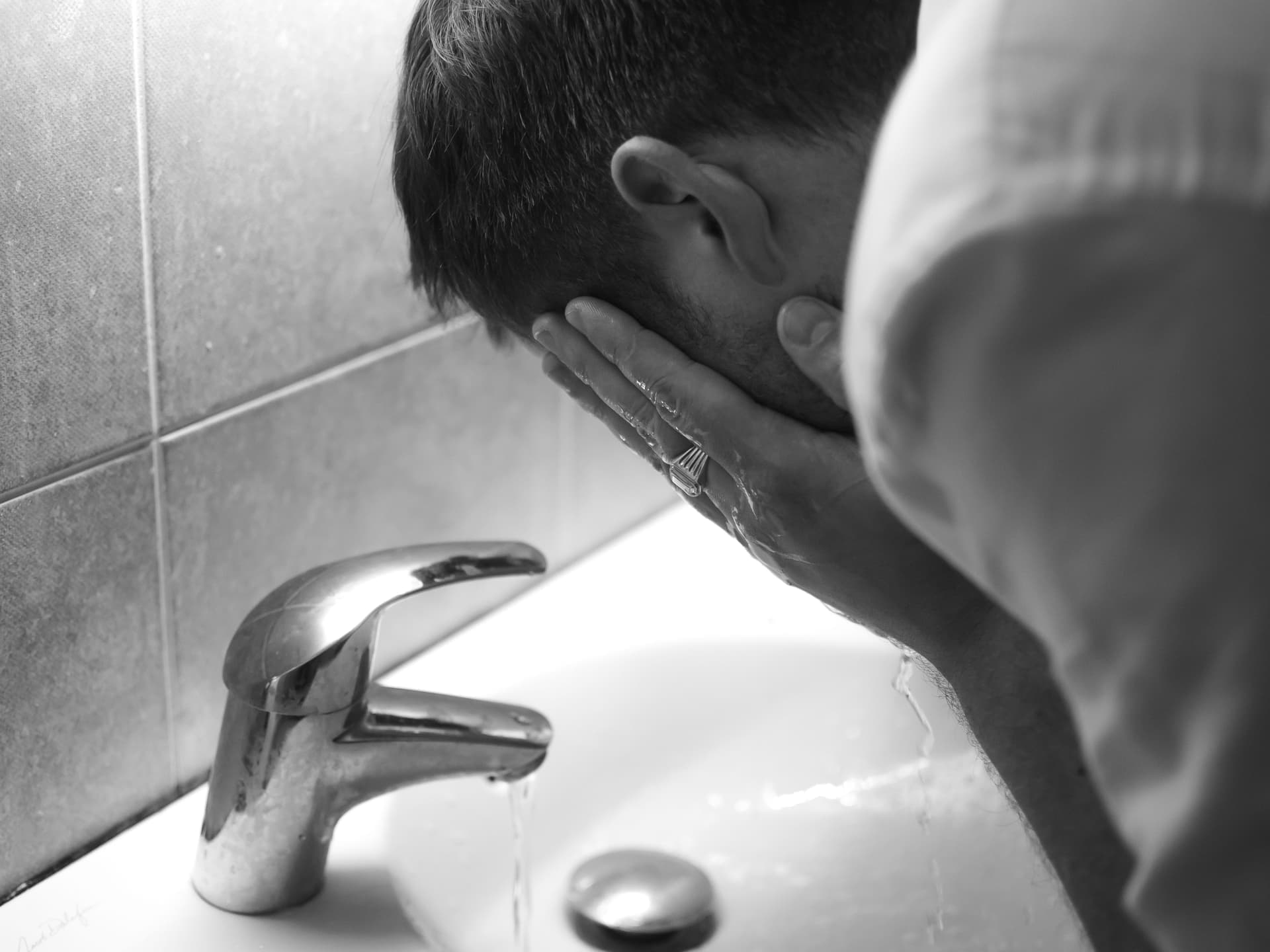 A man washing his face at a sink