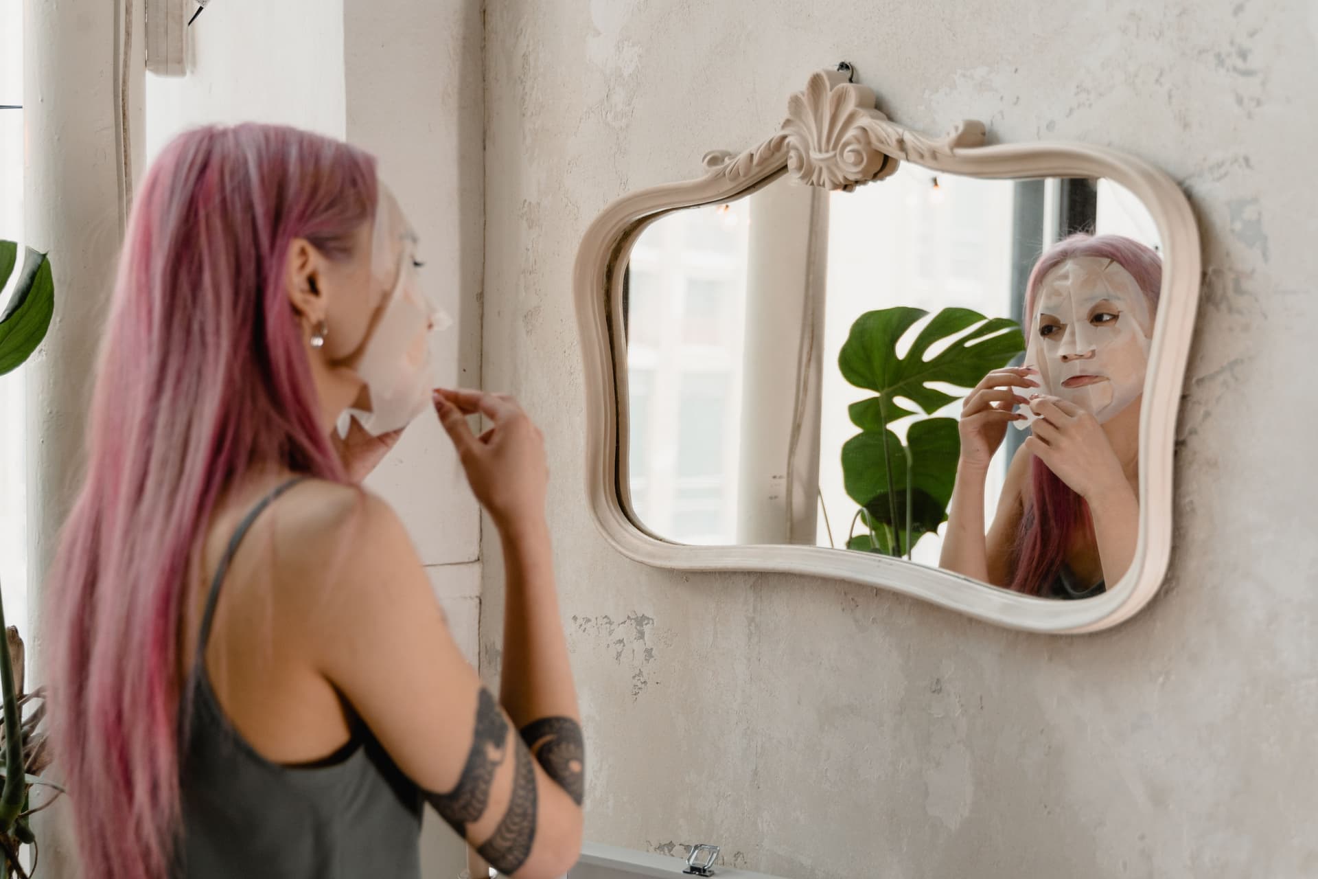 A woman looking into a mirror while applying skincare