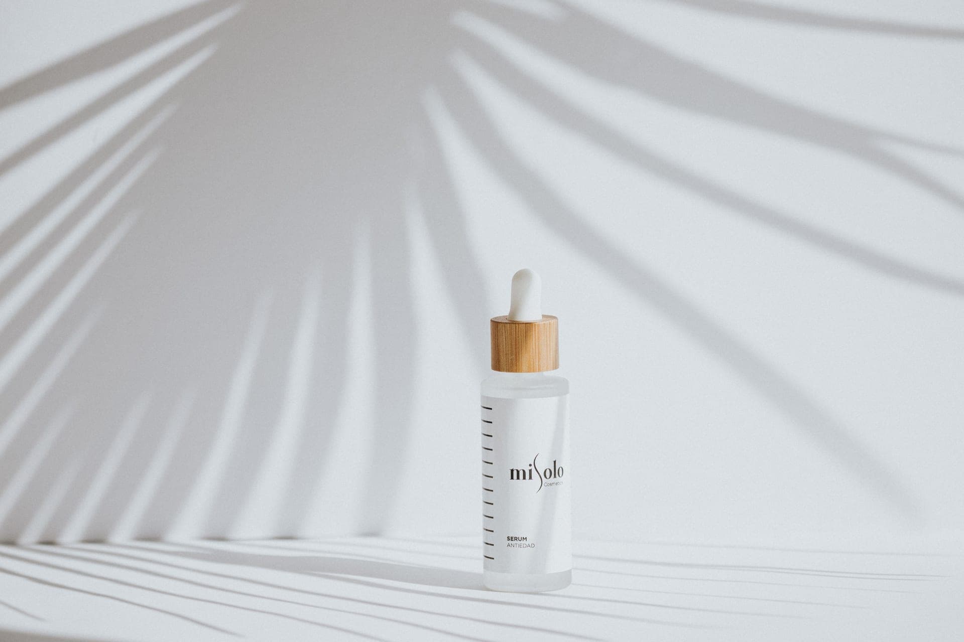 A single white cosmetic bottle casting a shadow on a pale surface
