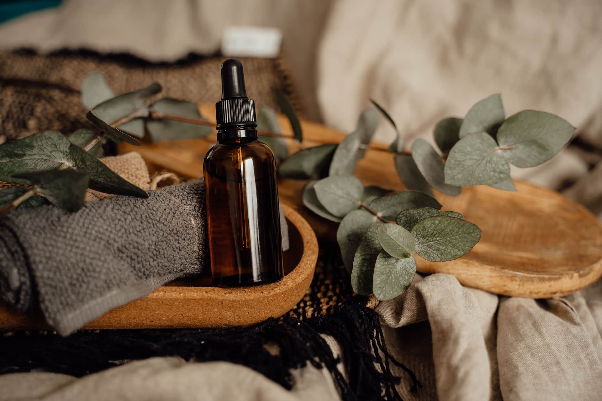 An amber dropper bottle beside eucalyptus leaves
