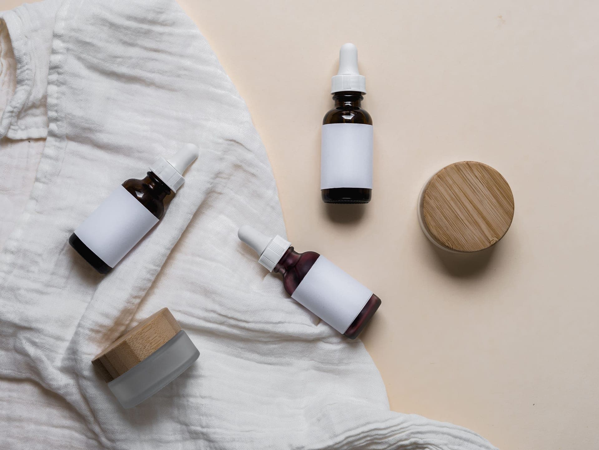 Glass skincare bottles with labels on textured fabric