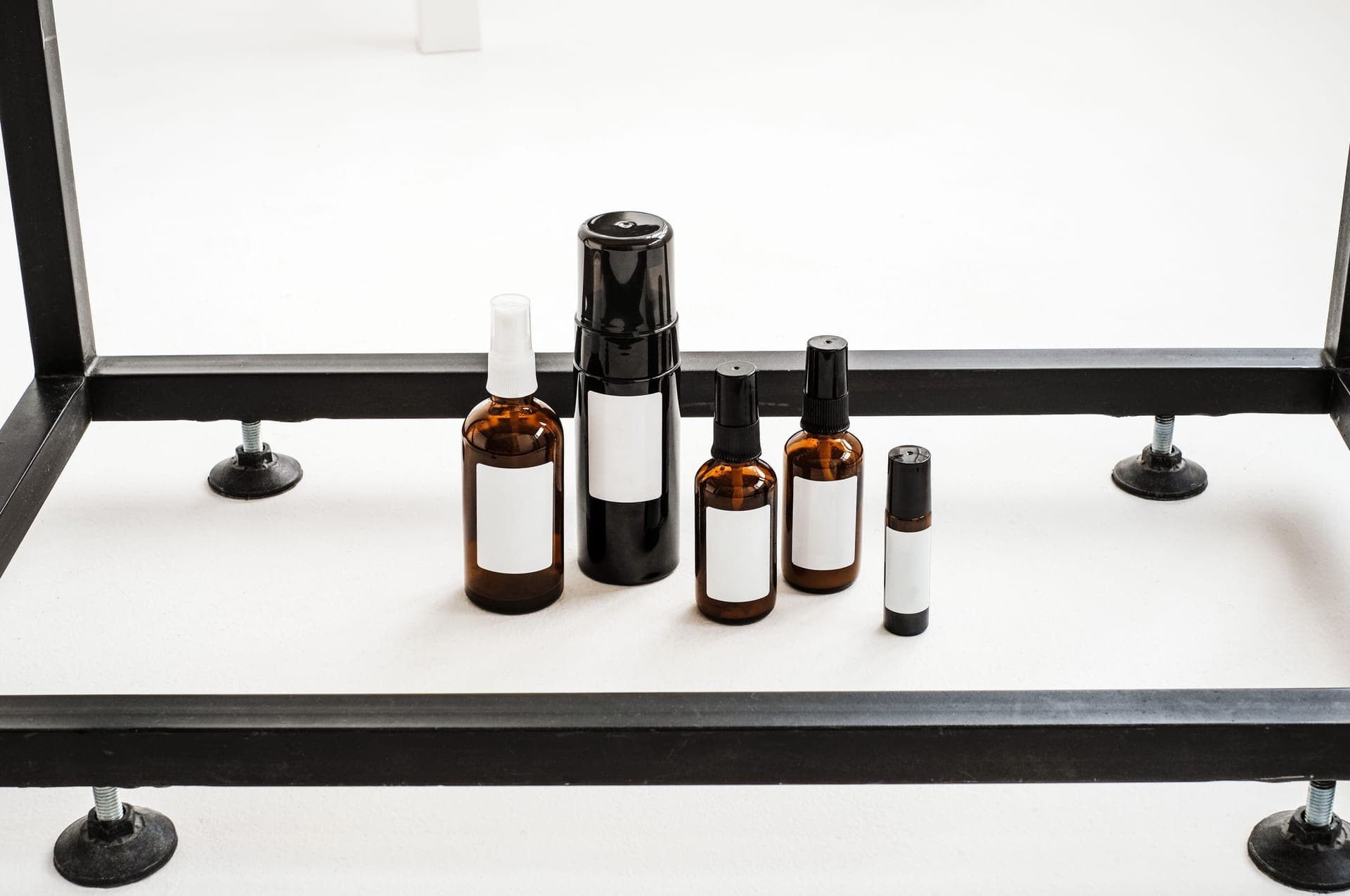 Glass skincare bottles on a pale display stand