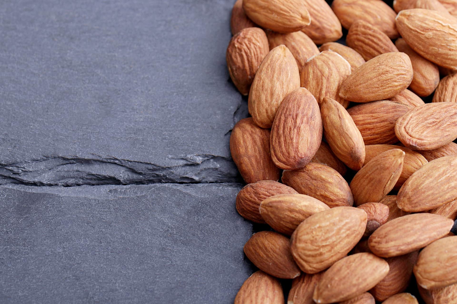 Close-up of raw almonds on a dark slate surface