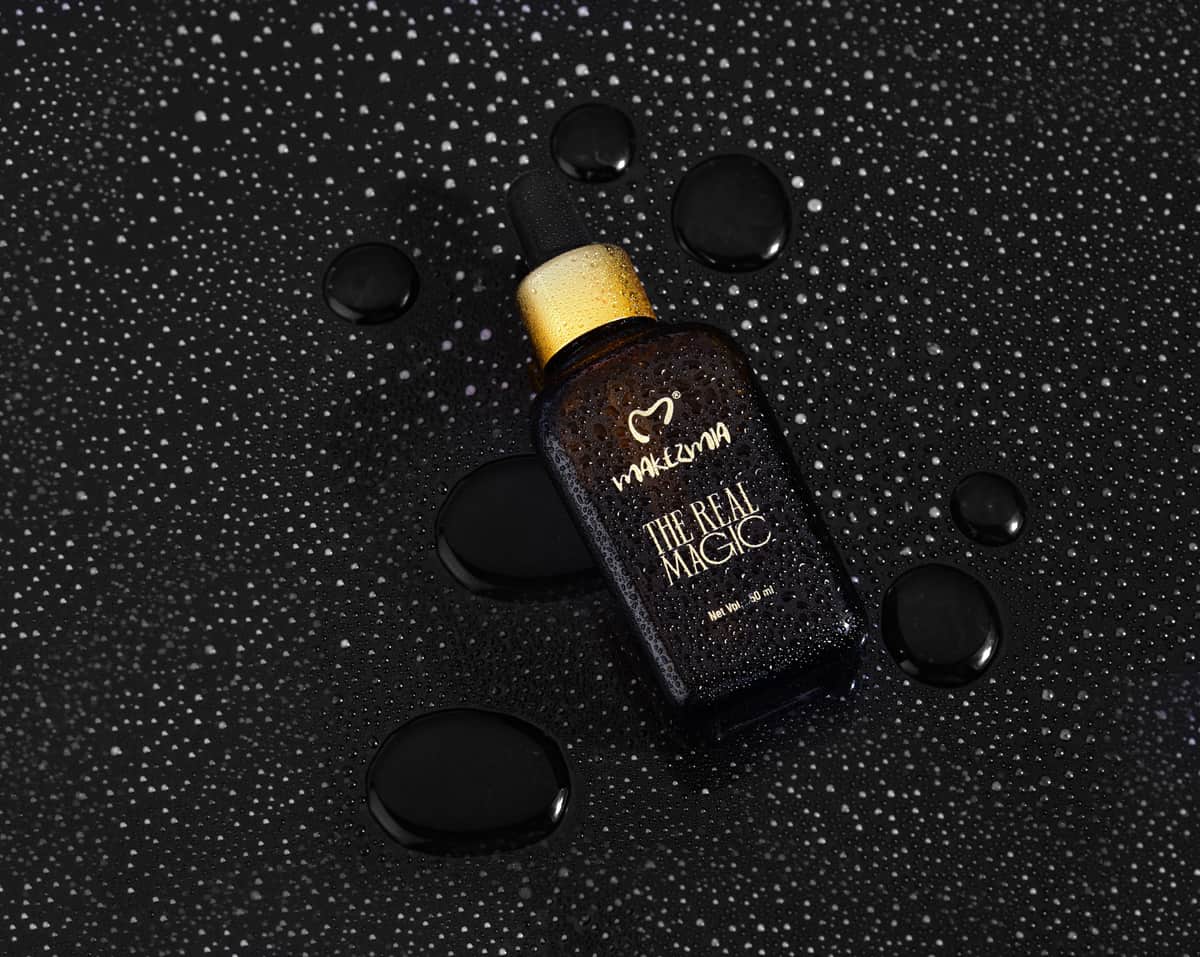 Golden facial oil in a dropper against a dark background