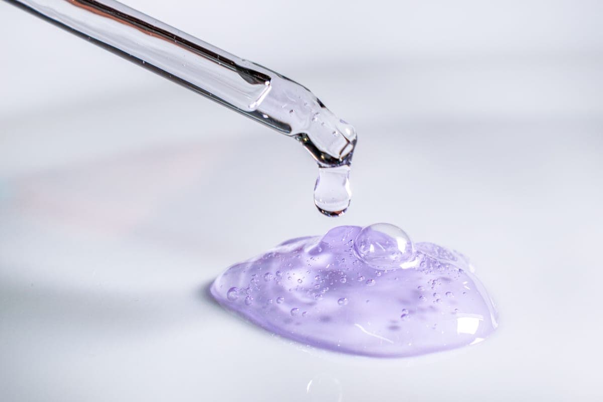 Laboratory pipette dispensing a clear serum, dark background