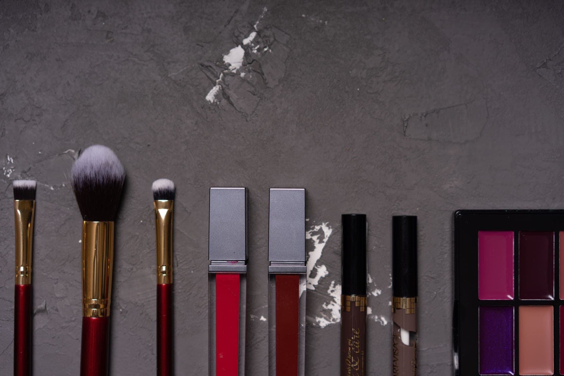 A small set of makeup products laid out on a pale surface