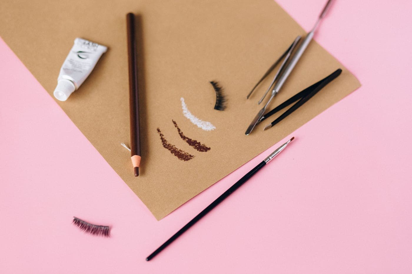 An eyebrow pencil and brushes arranged on a pale surface