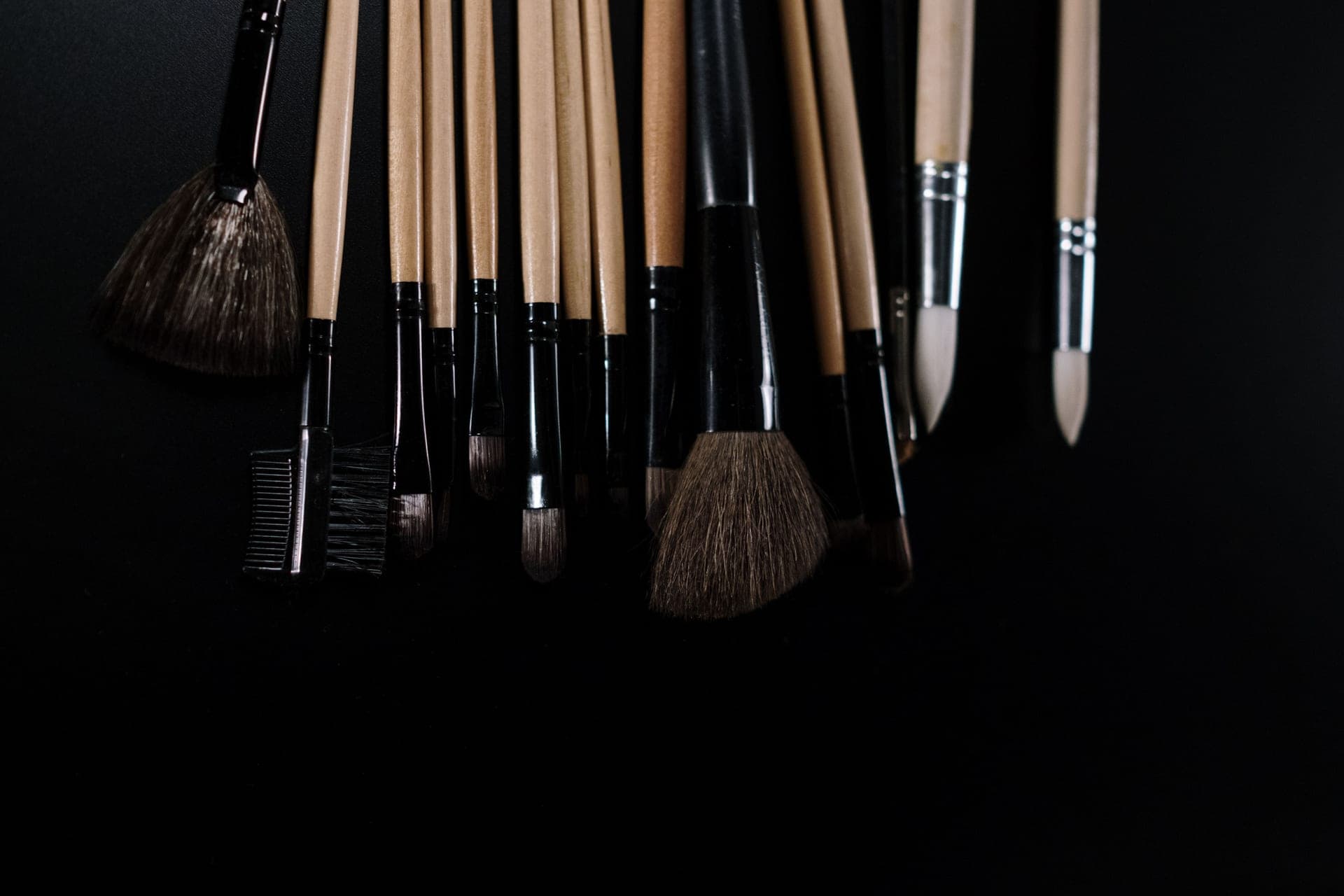 A fan of makeup brushes on a dark surface