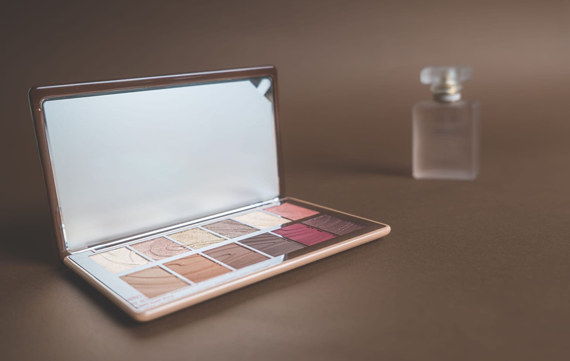 Makeup products and a palette arranged on a dark surface