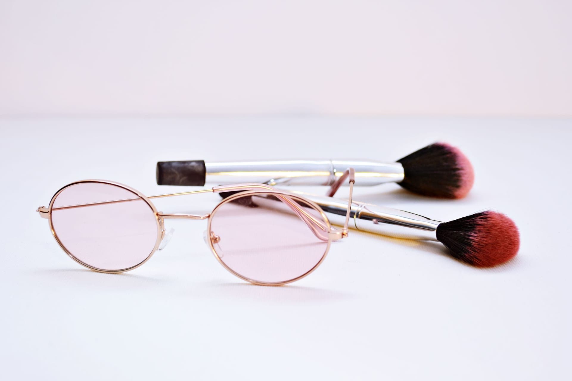 A pair of glasses resting beside makeup brushes