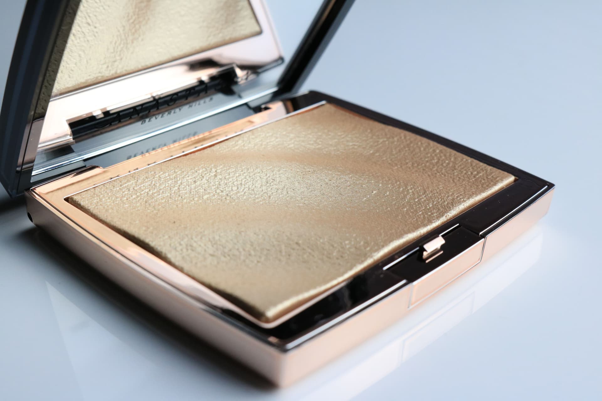 An open compact of shimmering gold powder