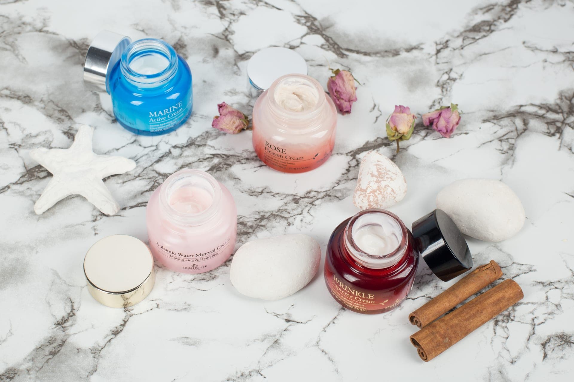 Cream makeup products arranged on a pale marble surface