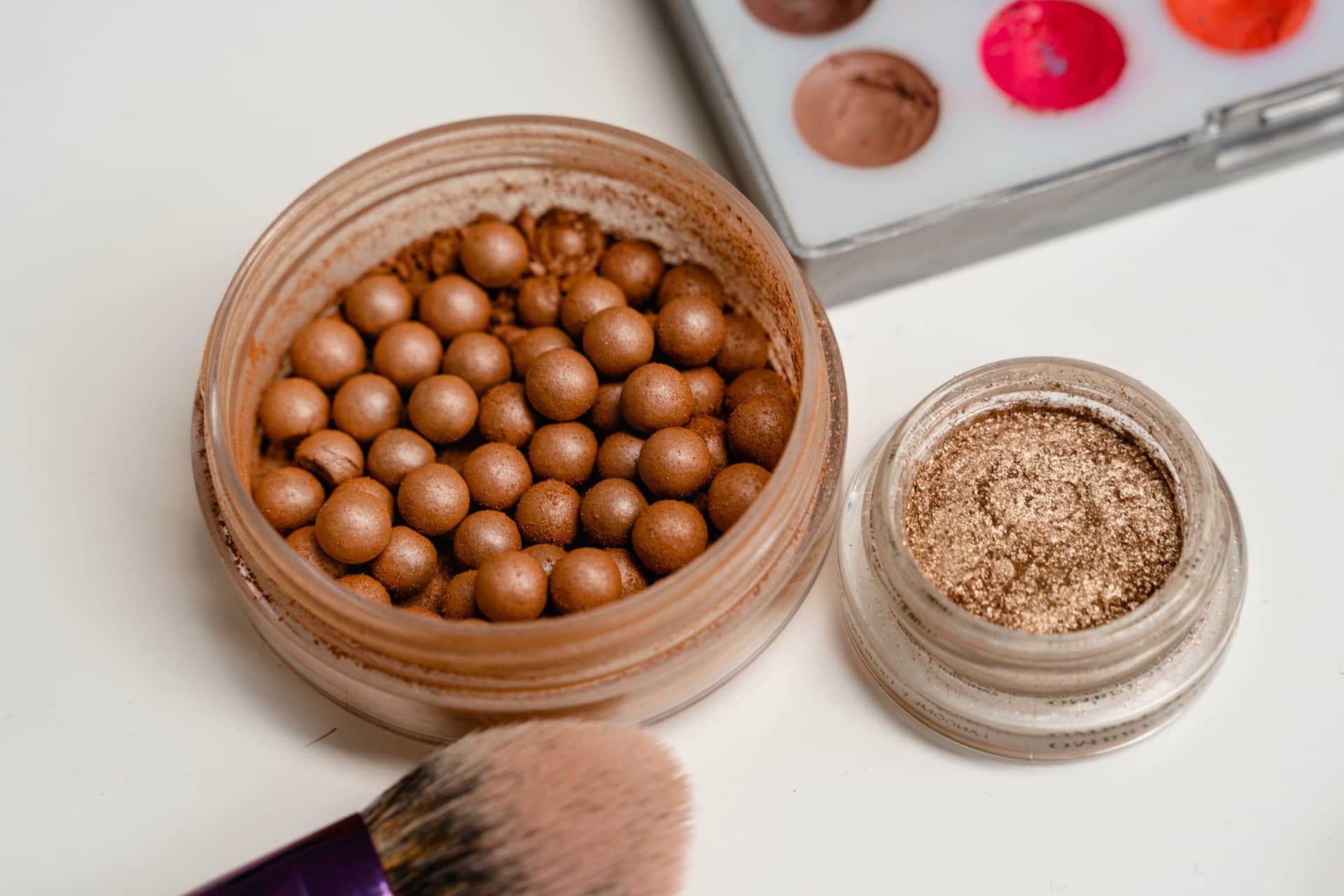 Bronze powder pearls, loose shimmer powder and a makeup brush
