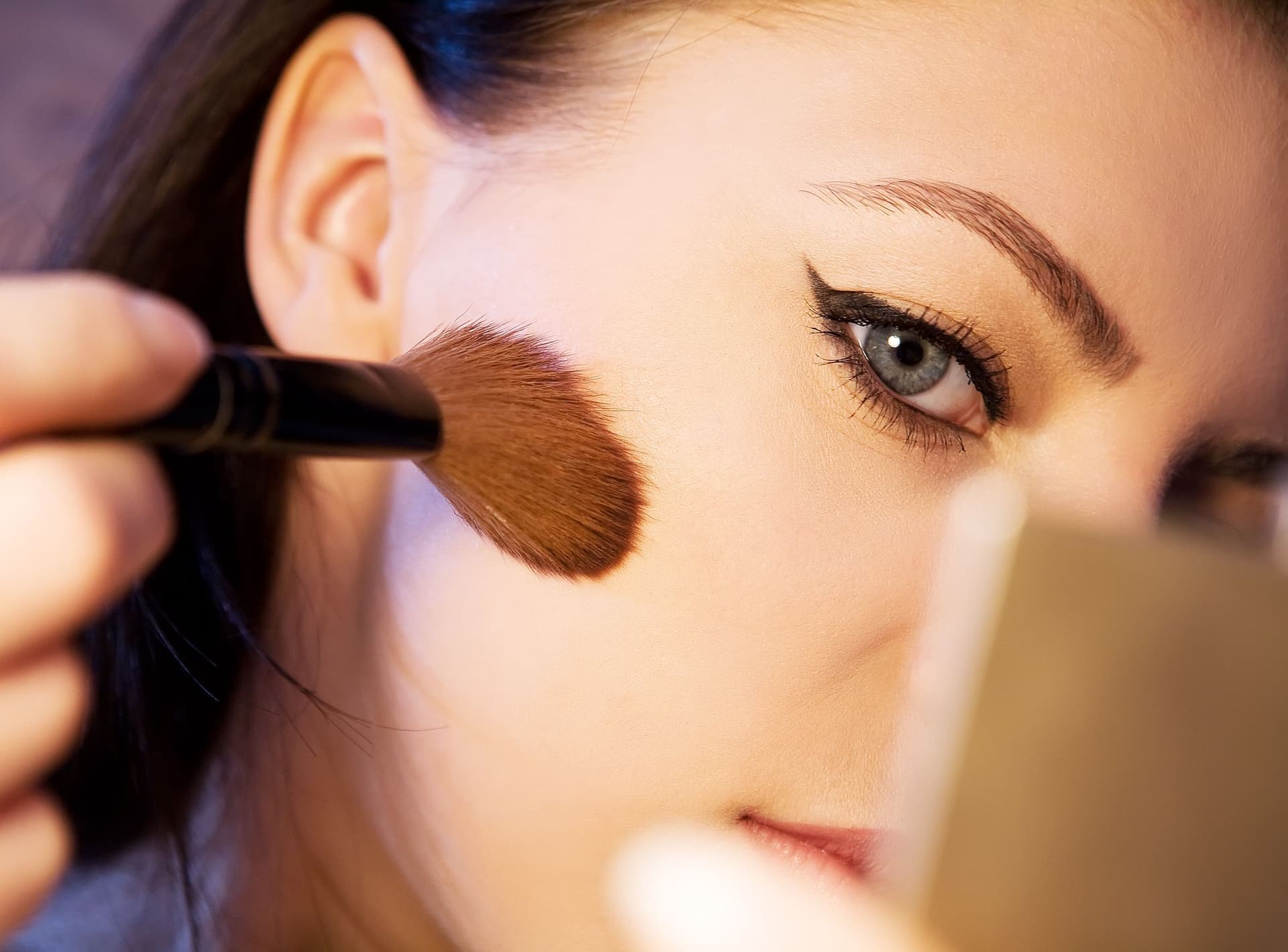 A woman applying makeup with a brush