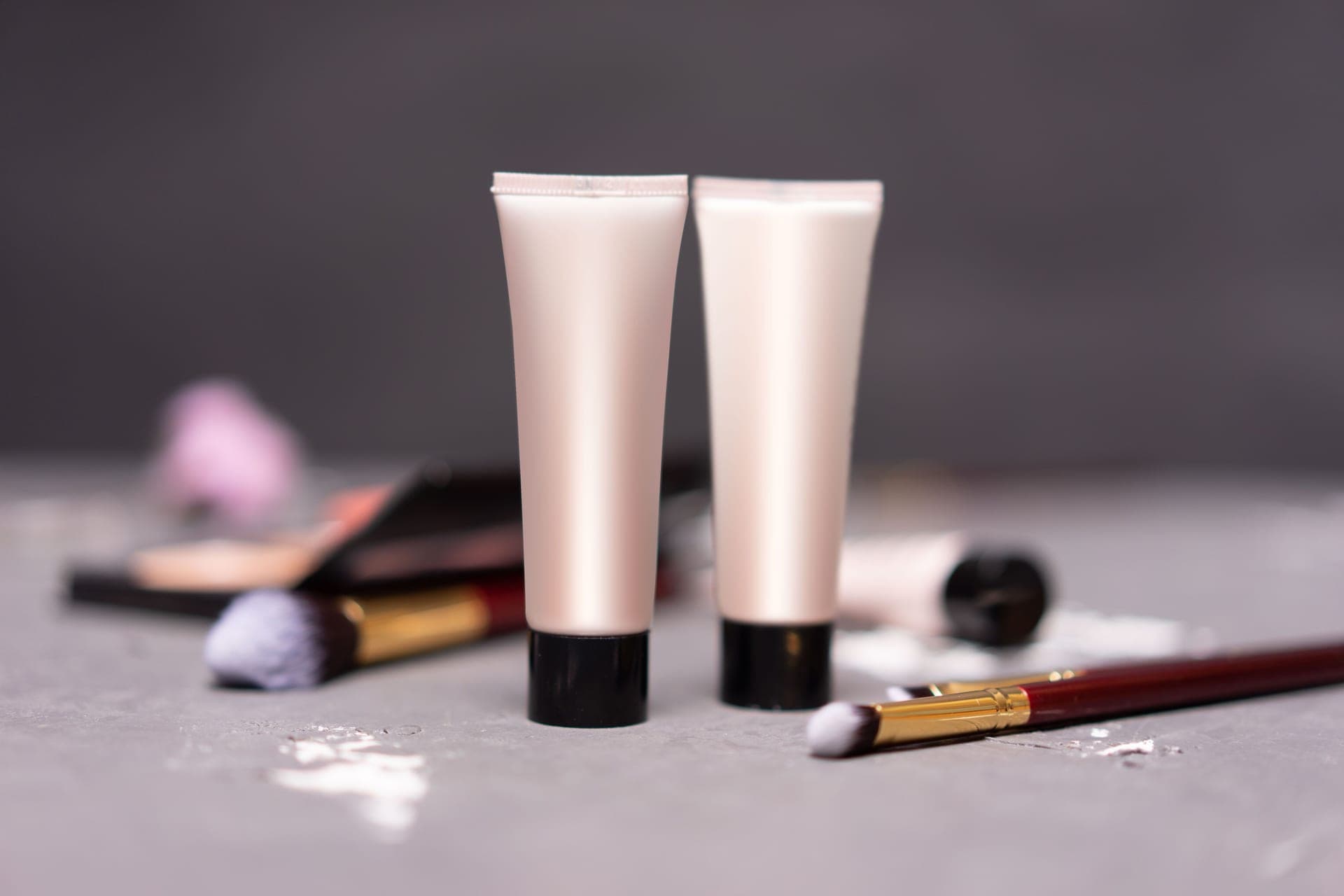 Two makeup tubes with brushes and a sponge