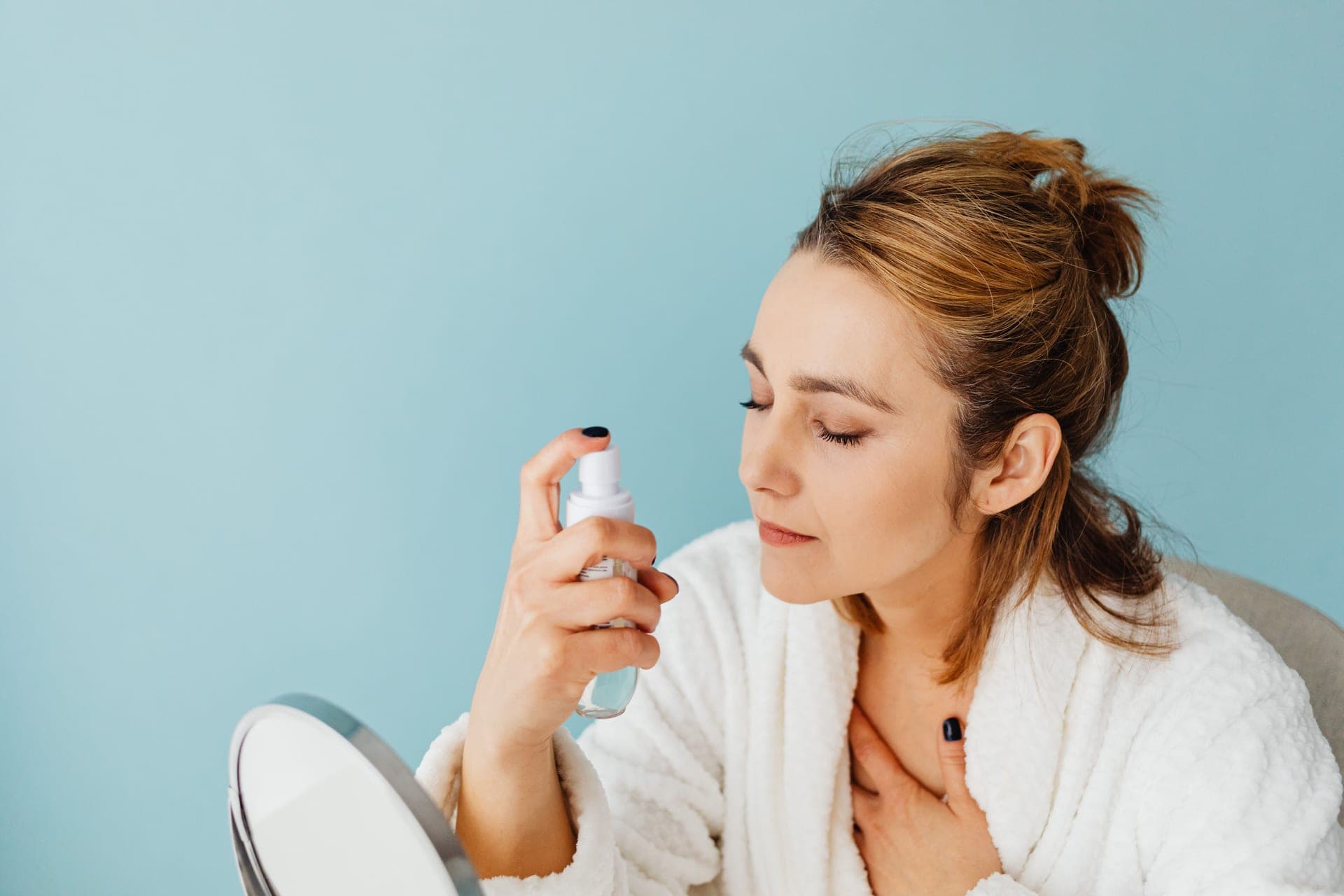 A woman misting her face with a spray bottle