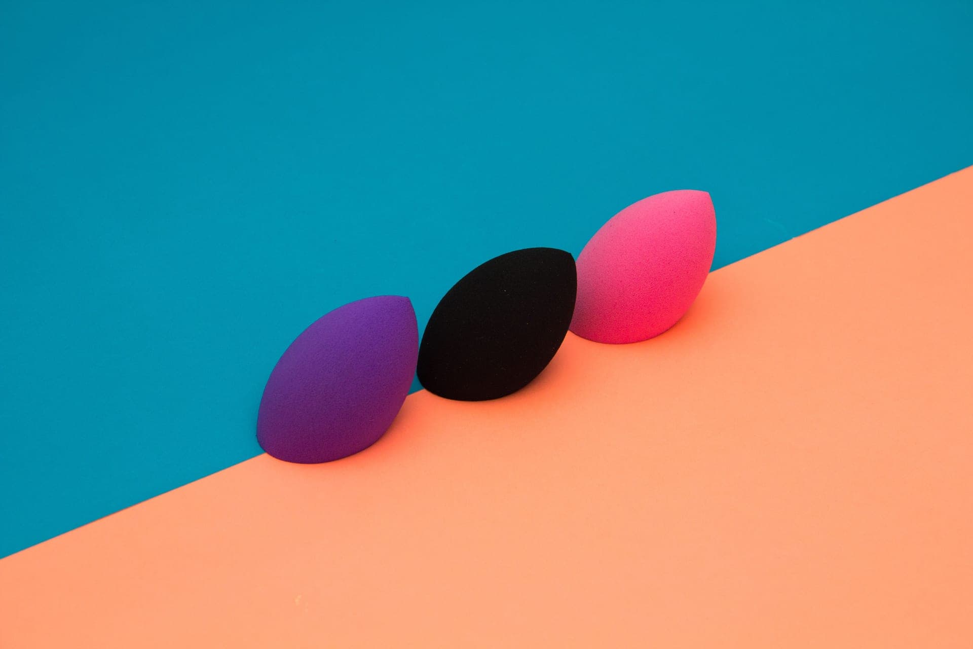 Three makeup sponges on a two-tone background