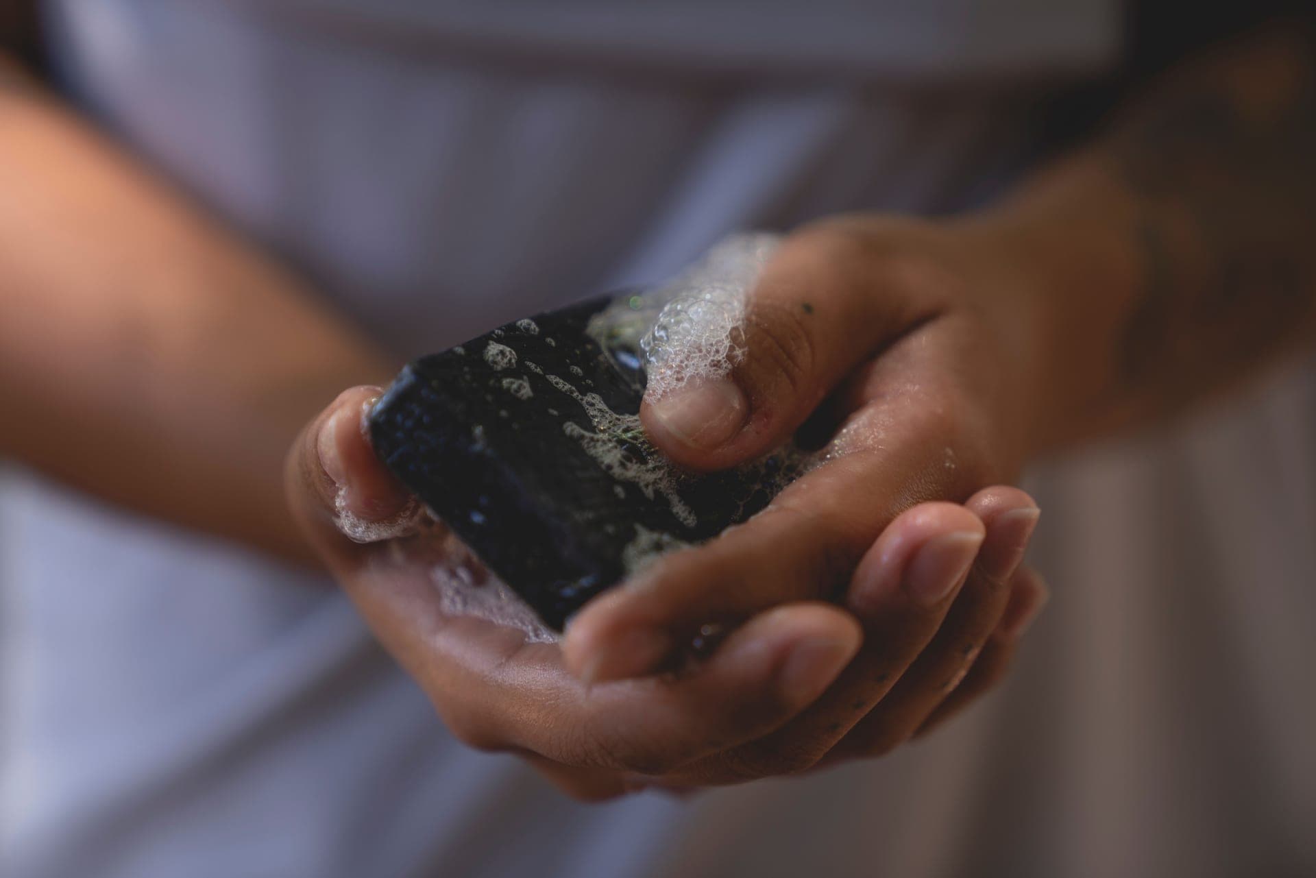 Hands lathering a dark bar of soap