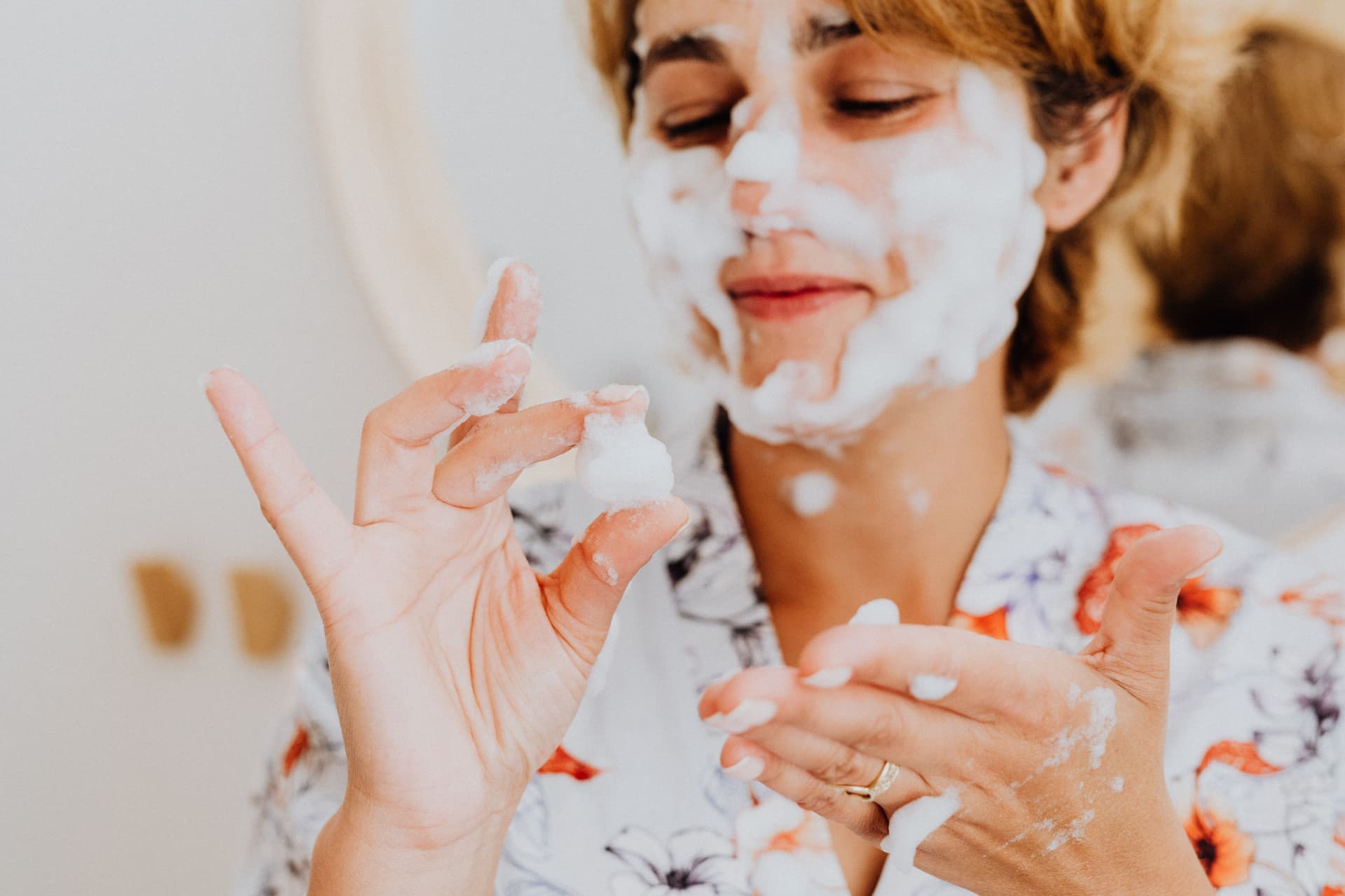 A woman lathering foaming cleanser on her face