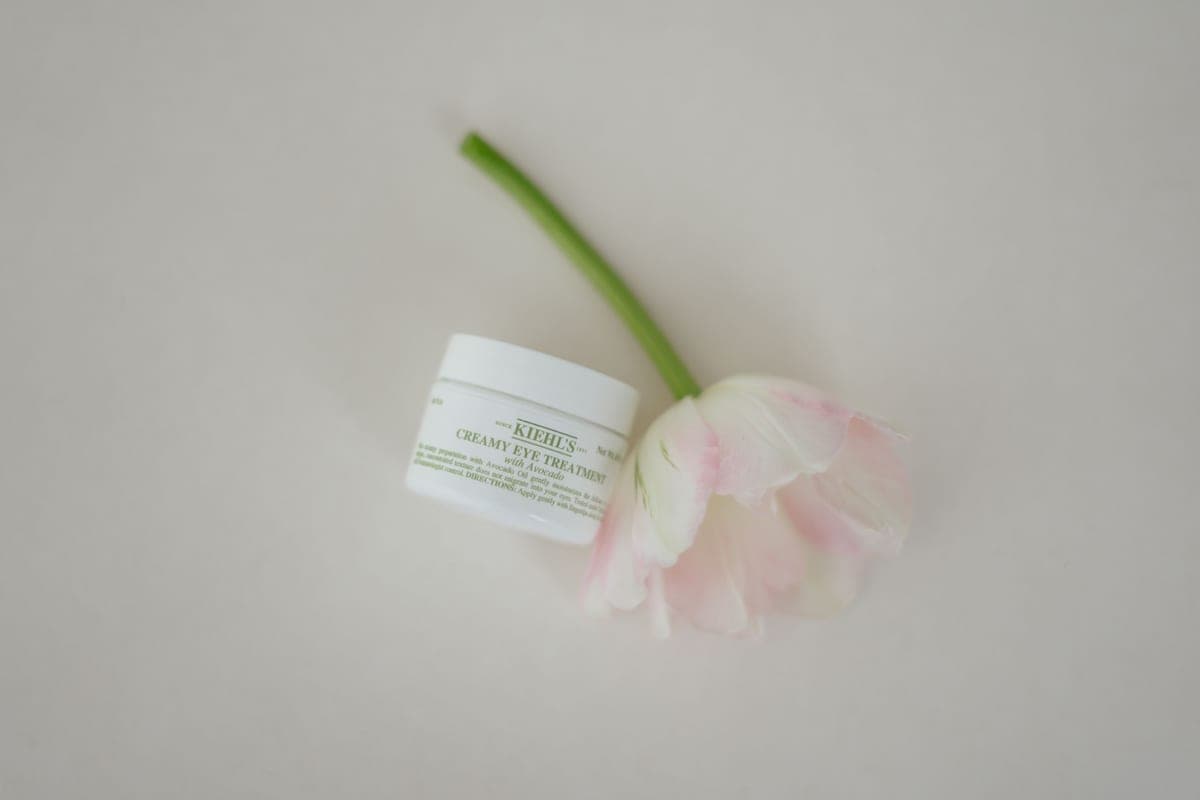 A small jar of eye cream photographed close up on a dark surface