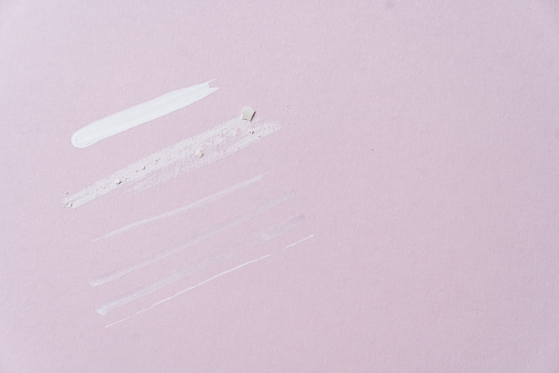 Swatches of a white cream on a pale pink surface