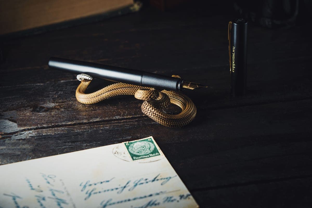 A dark desk with an envelope and a pen
