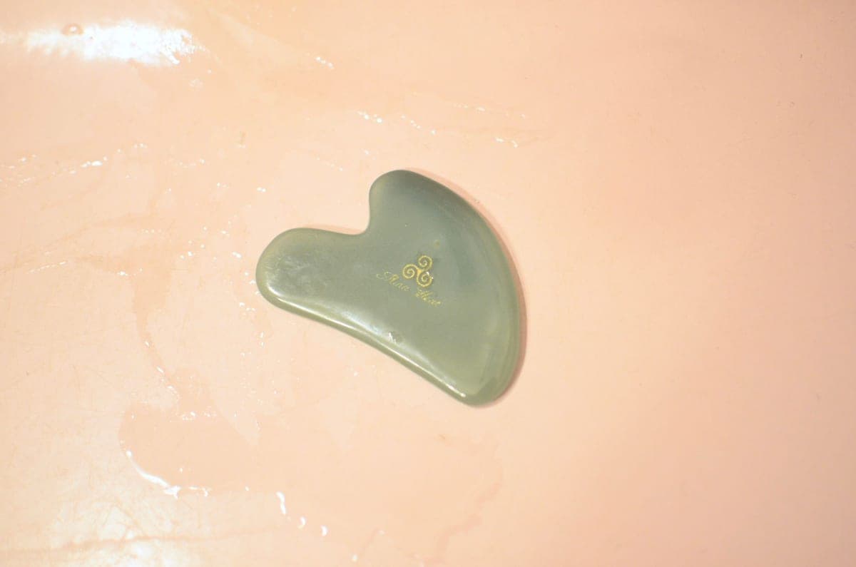 A gua sha stone resting on dark fabric