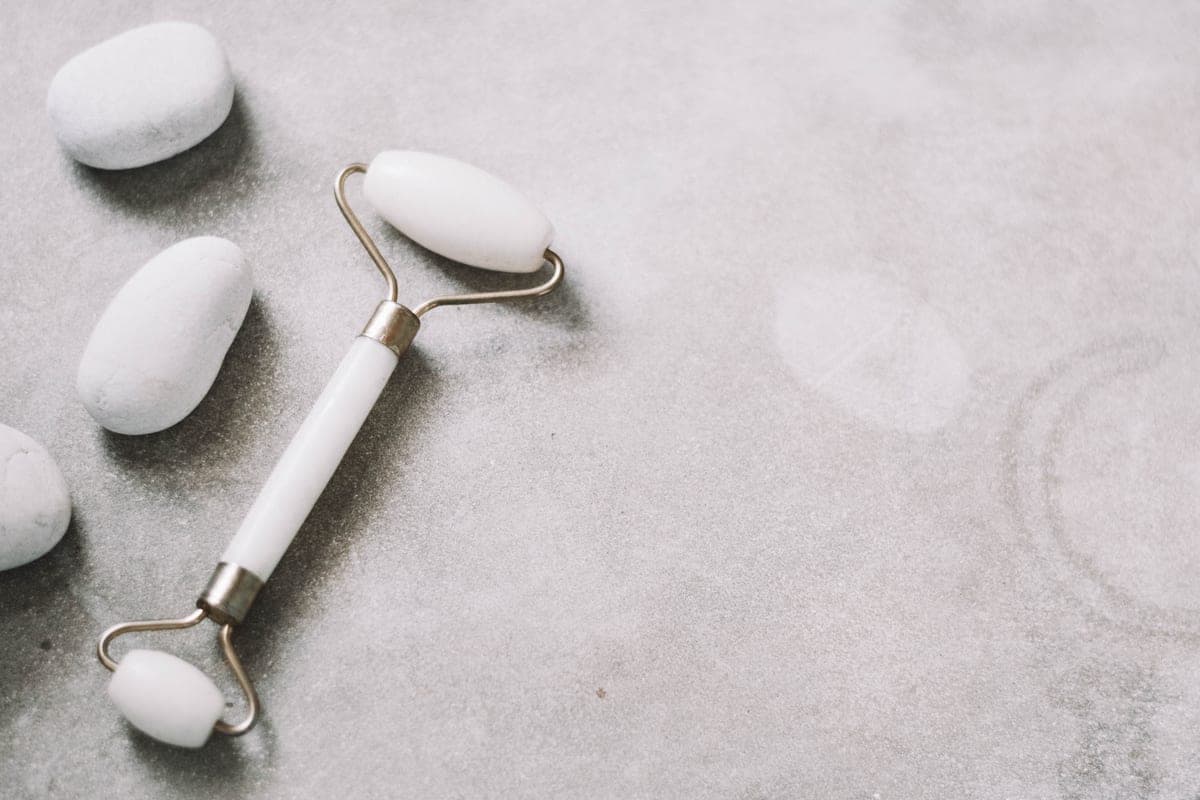 A jade facial roller on a dark surface