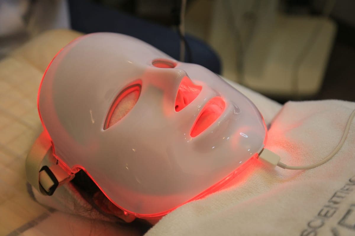 An LED light therapy face mask on a dark surface